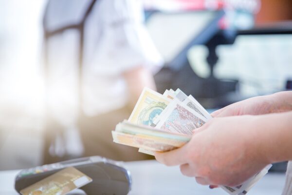 Person counting Omani banknotes near a payment terminal, representing secure and low-fee Money Transfer to Pakistan from Oman.
