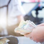 Hands counting currency notes at a payment counter, representing how customers send money to Egypt online securely